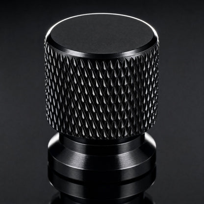 Close-up of a black anodised aluminium valve cap showing the machined diamond knurl and chamfered top