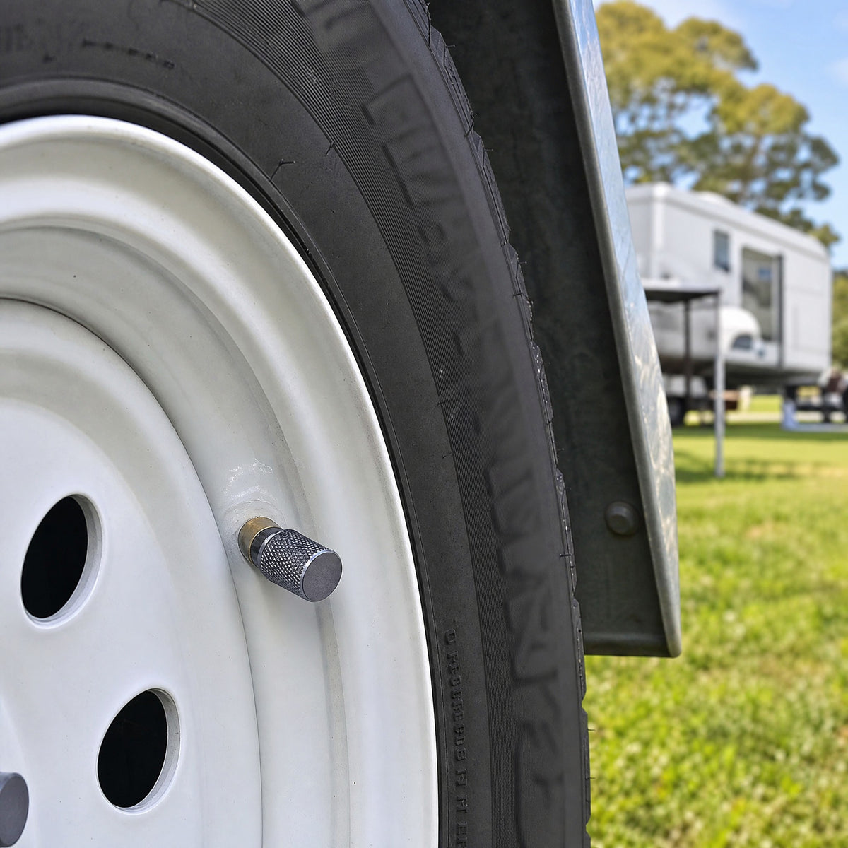 Grey aluminium valve cap on a white steel camper trailer wheel